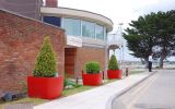In bold Coral Red colour, the planters create a strong visual line along walkways.